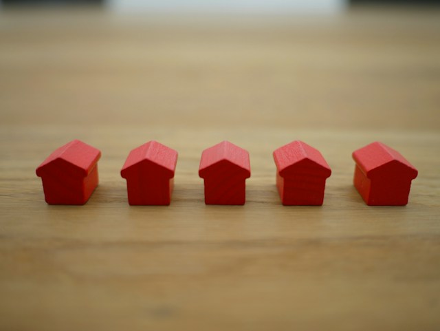 five little red home figurines in a row